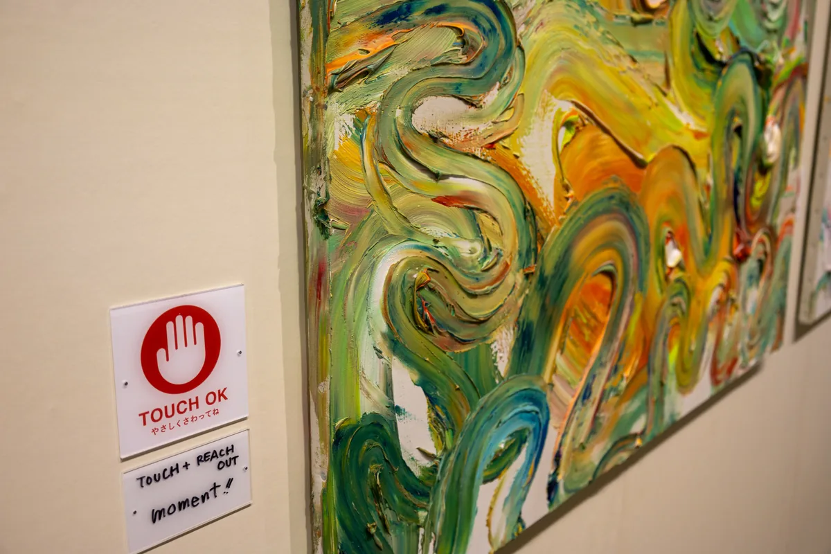 「TOUCH OK やさしくさわってね」のマークと、絵の具を厚く盛り上げた木梨憲武さんの触れる作品
