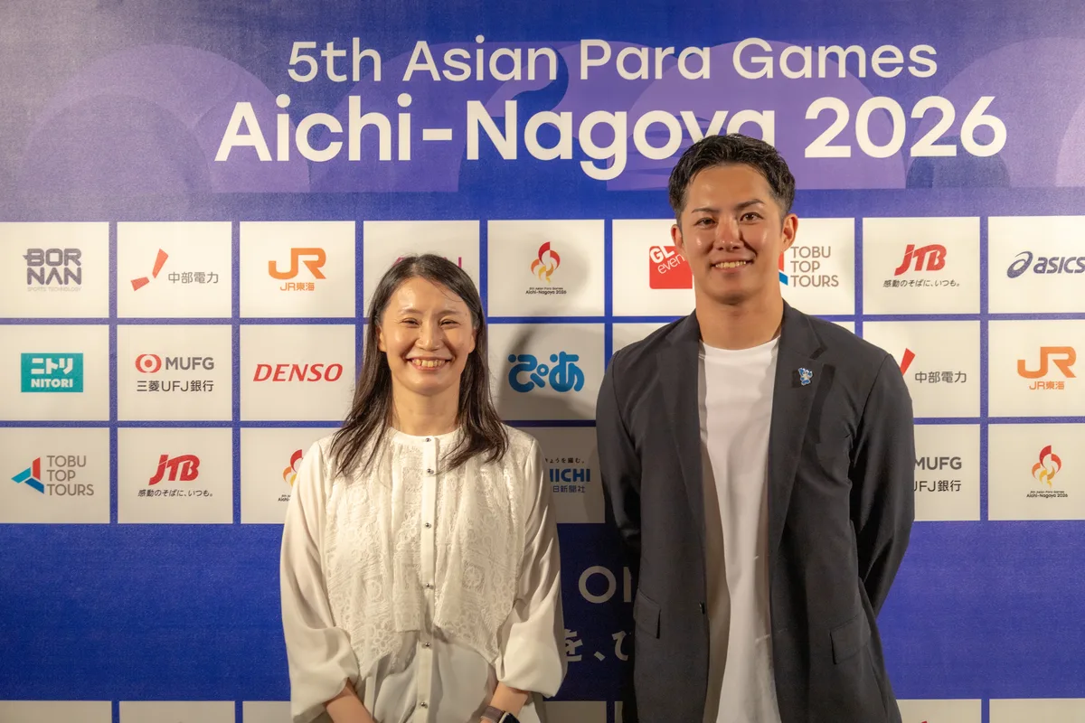 インタビューのあと、大会のスポンサーボードの前に並ぶ伊藤則子さんと小須田潤太さん