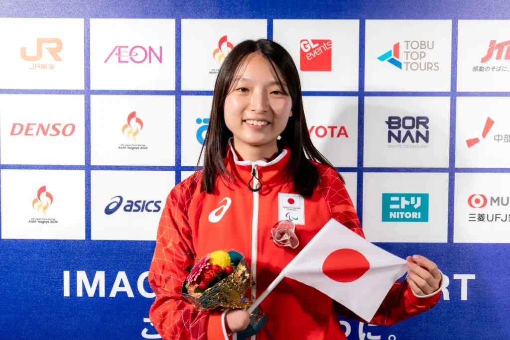 日の丸の小旗と花束を手にするパラ陸上の中川もえ選手