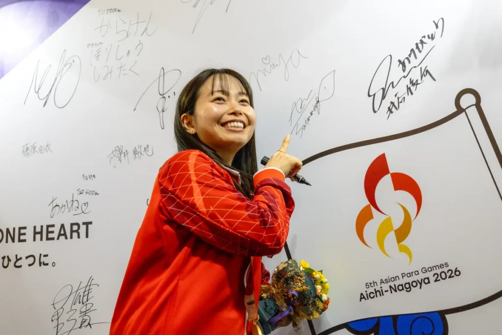 ライブサイトのサインウォールにサインし、指をさす西田杏選手