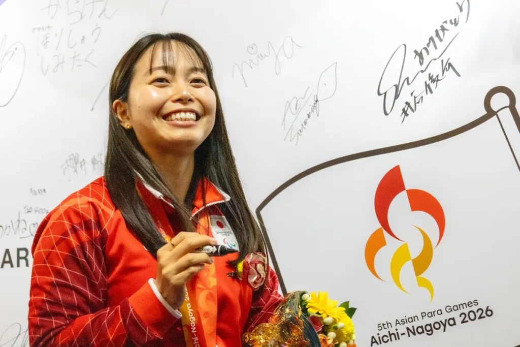 ライブサイトのサインウォールの前で笑顔を見せる西田杏選手