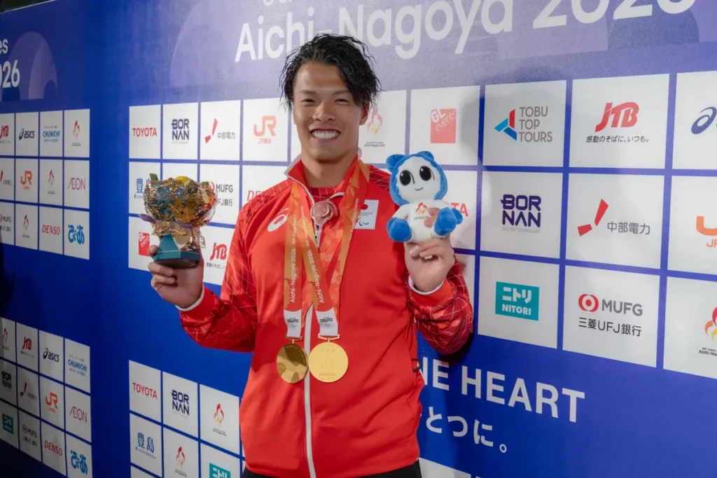 2つの金メダルを掛けて花束とウズミンのぬいぐるみを手にする大島健吾選手