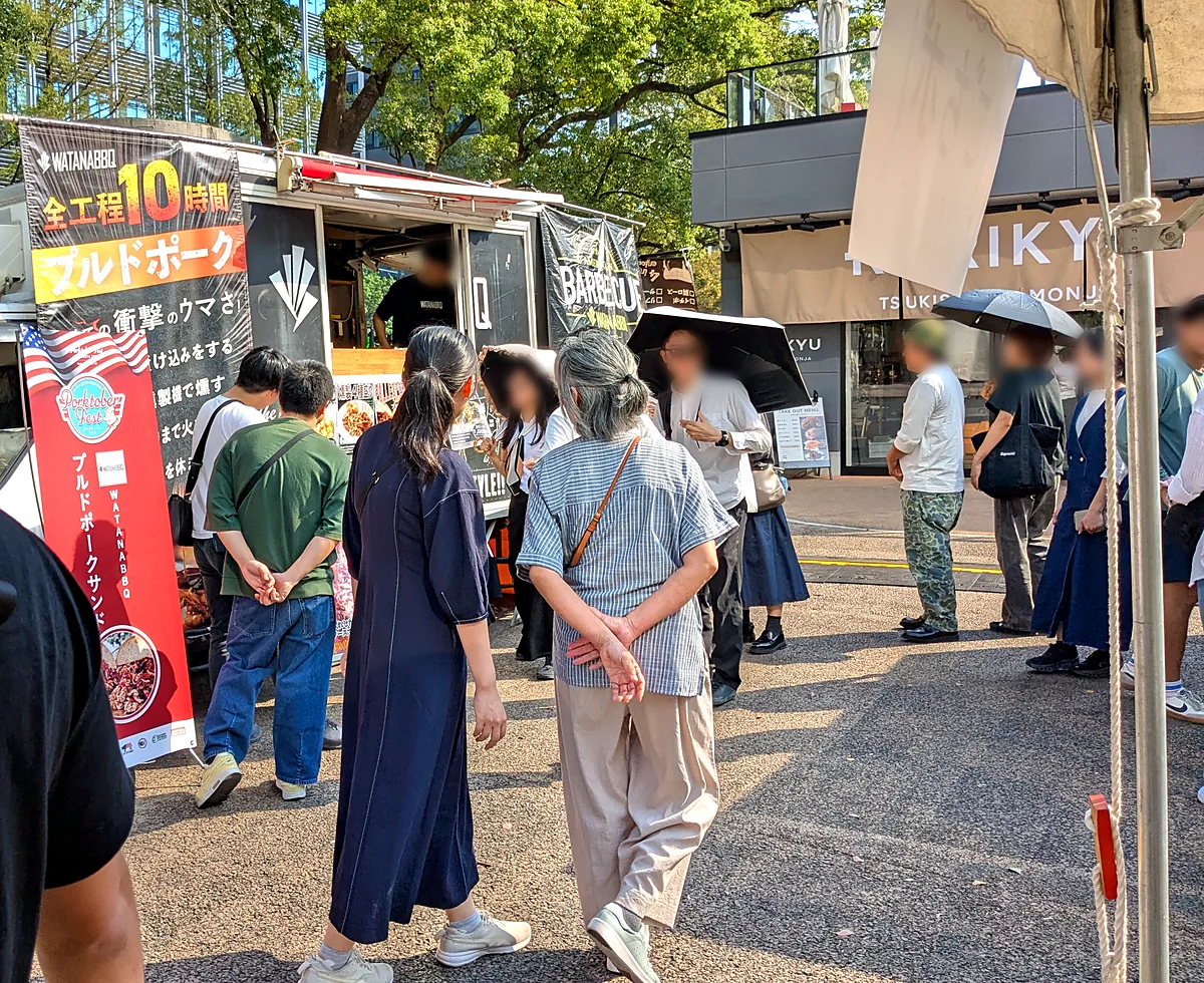 WATANABBQのキッチンカー。「全工程10時間 プルドポーク」の看板の前に並ぶ人