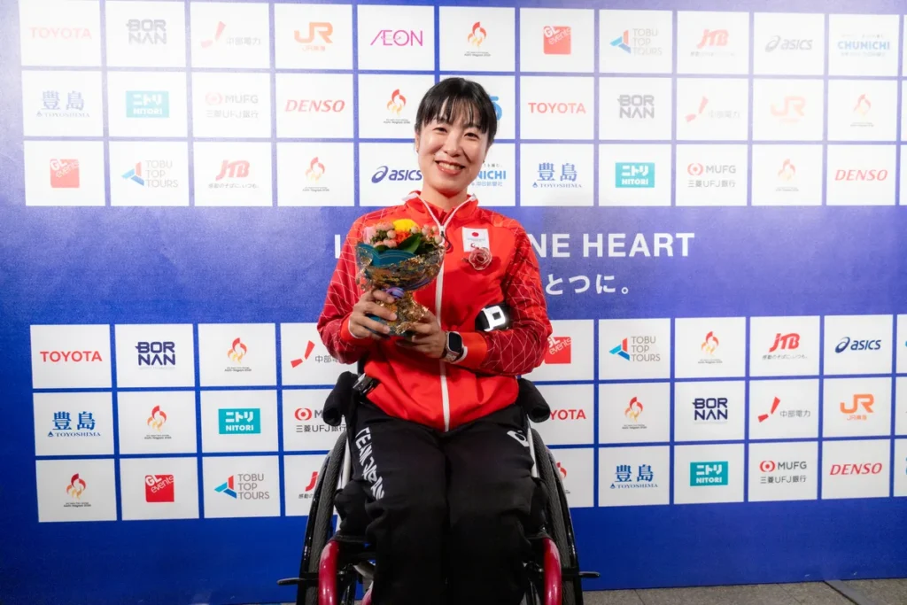花束を手に車いすでミックスゾーンに座る篠原彩選手
