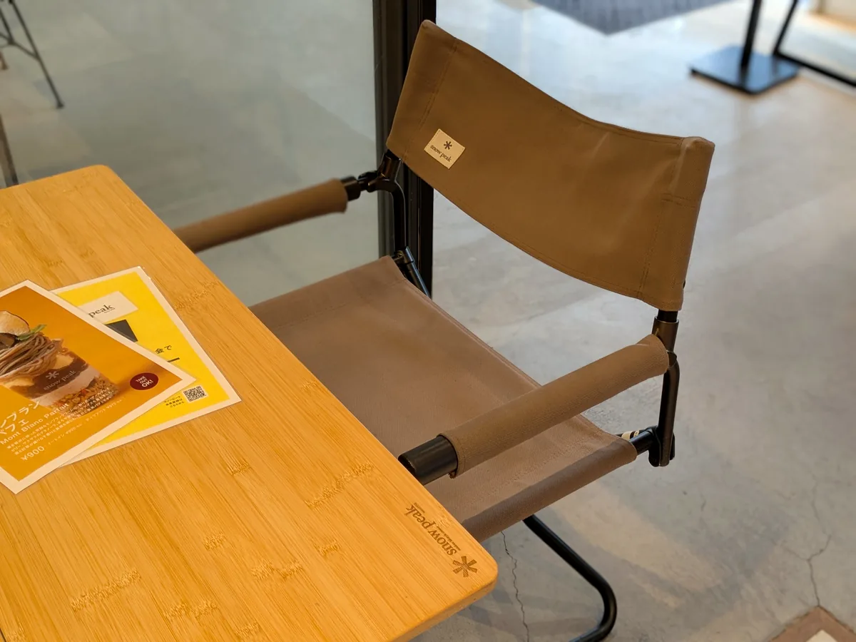 スノーピークのロゴが入った折りたたみチェアと竹のテーブル。卓上にはモンブランパフェと会員登録の案内