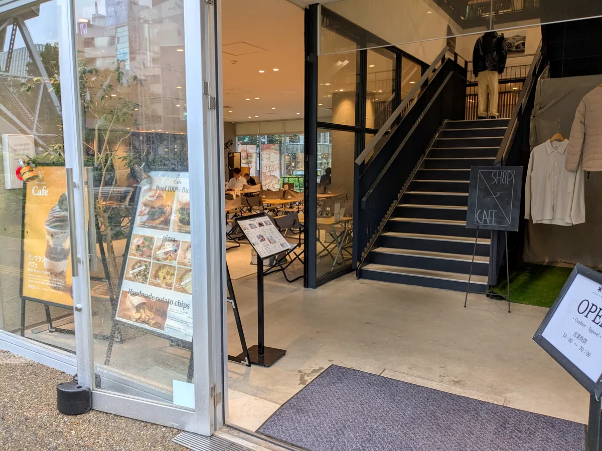 スノーピークカフェ久屋大通公園店の入口。ビーフ100%バーガーとピザ、手作りポテトチップスのメニュー板とモンブランパフェの看板