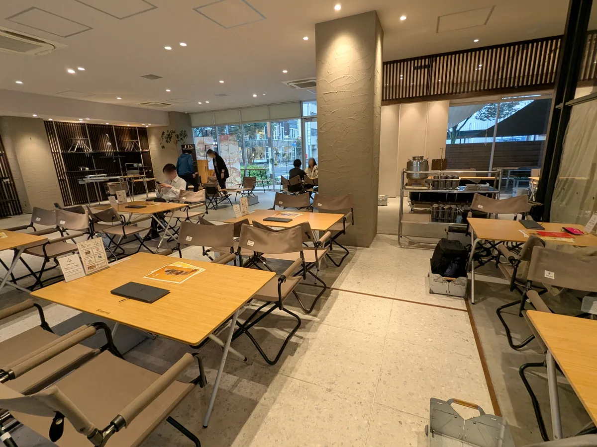 スノーピークカフェ久屋大通公園店の店内。スノーピークの折りたたみチェアと竹の天板のテーブルが並ぶ