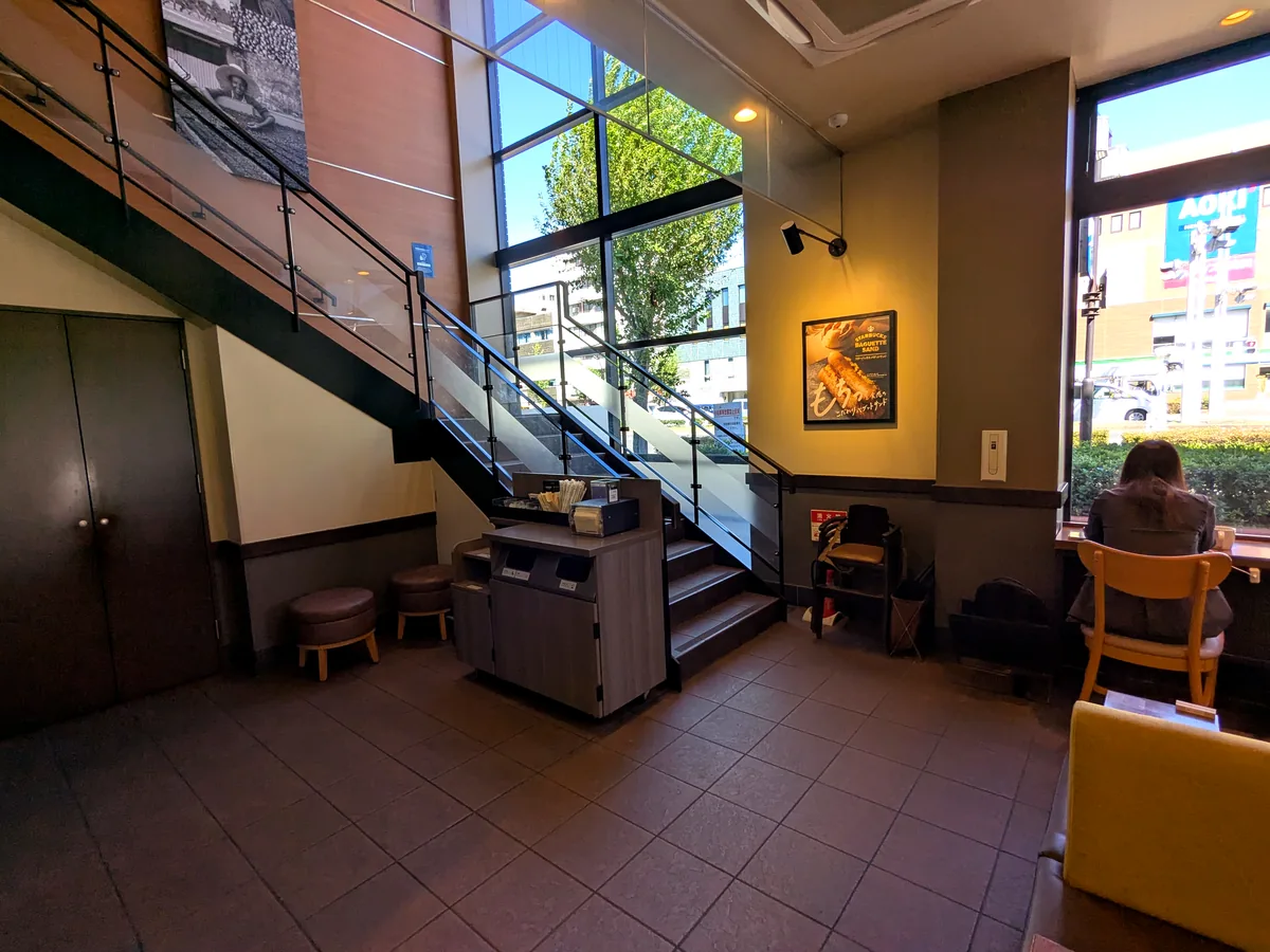 スターバックス御器所駅前店の1階。吹き抜けの窓と2階へ上がる階段、窓際のカウンター席