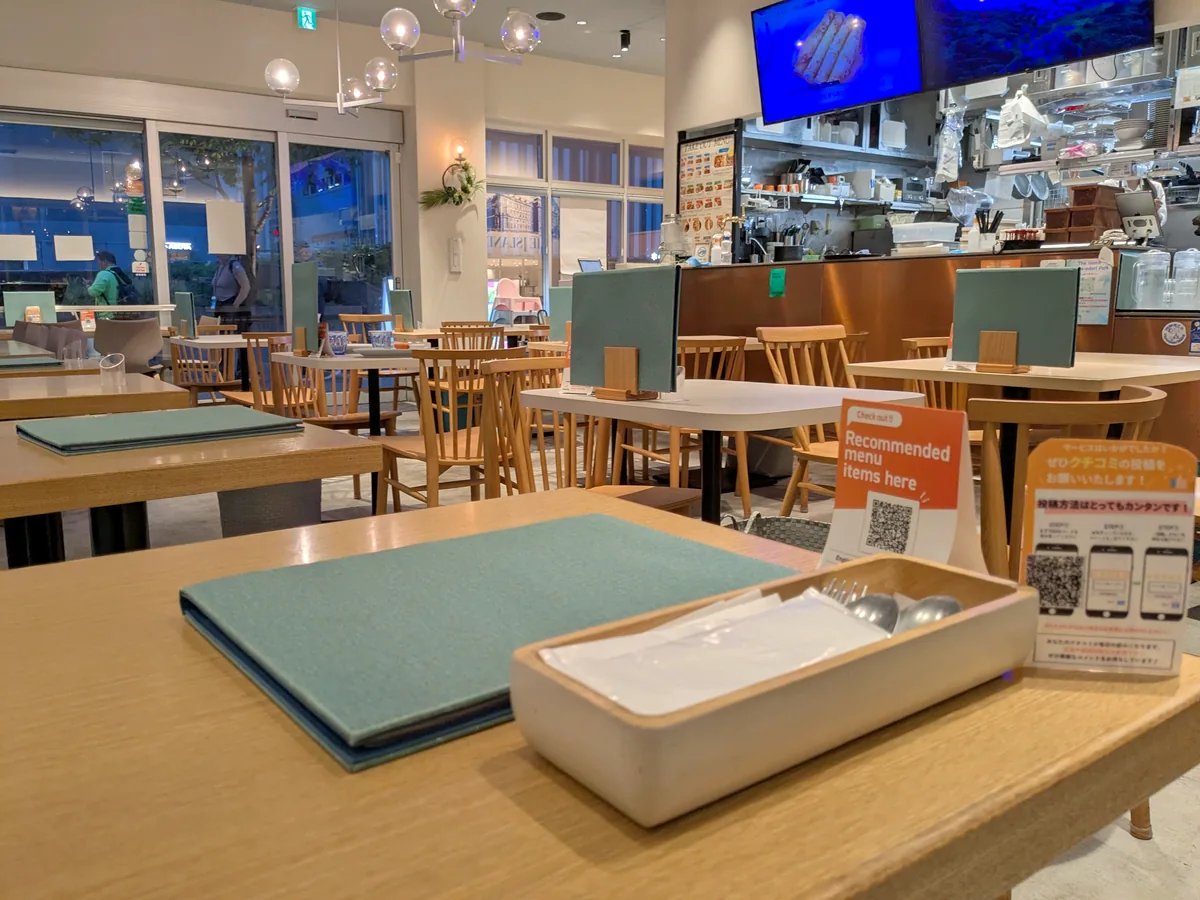 木のテーブルといすが並ぶTHE ISLAND 久屋大通パーク店の明るい店内