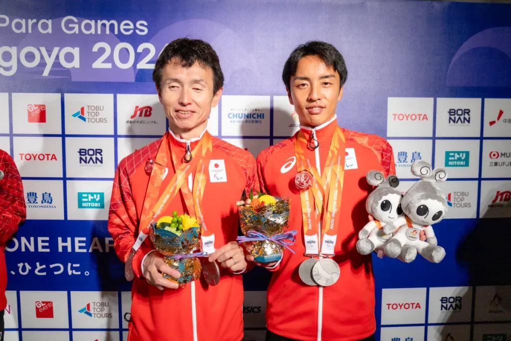 銀メダルと花束、ウズミンのぬいぐるみを手にミックスゾーンに立つ和田伸也選手と長谷部匠さん