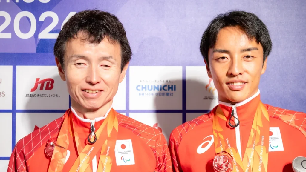 パラ陸上の和田伸也選手とガイドランナーの長谷部匠さん。銀メダルを掛けて