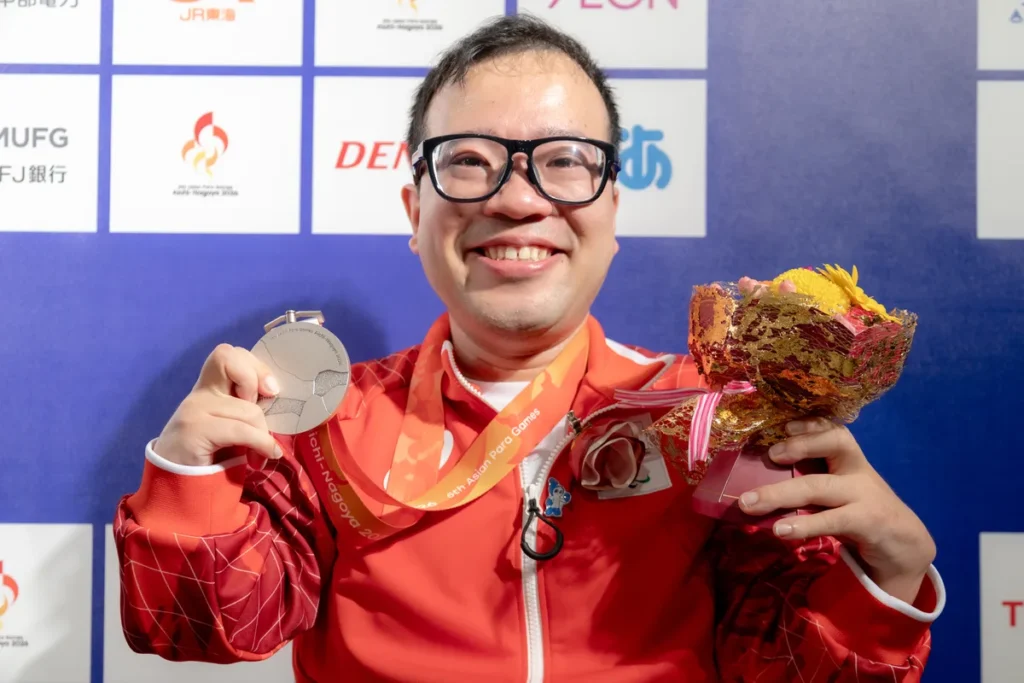 ミックスゾーンで銀メダルと花束を手に笑顔を見せるパラ卓球の八木克勝選手