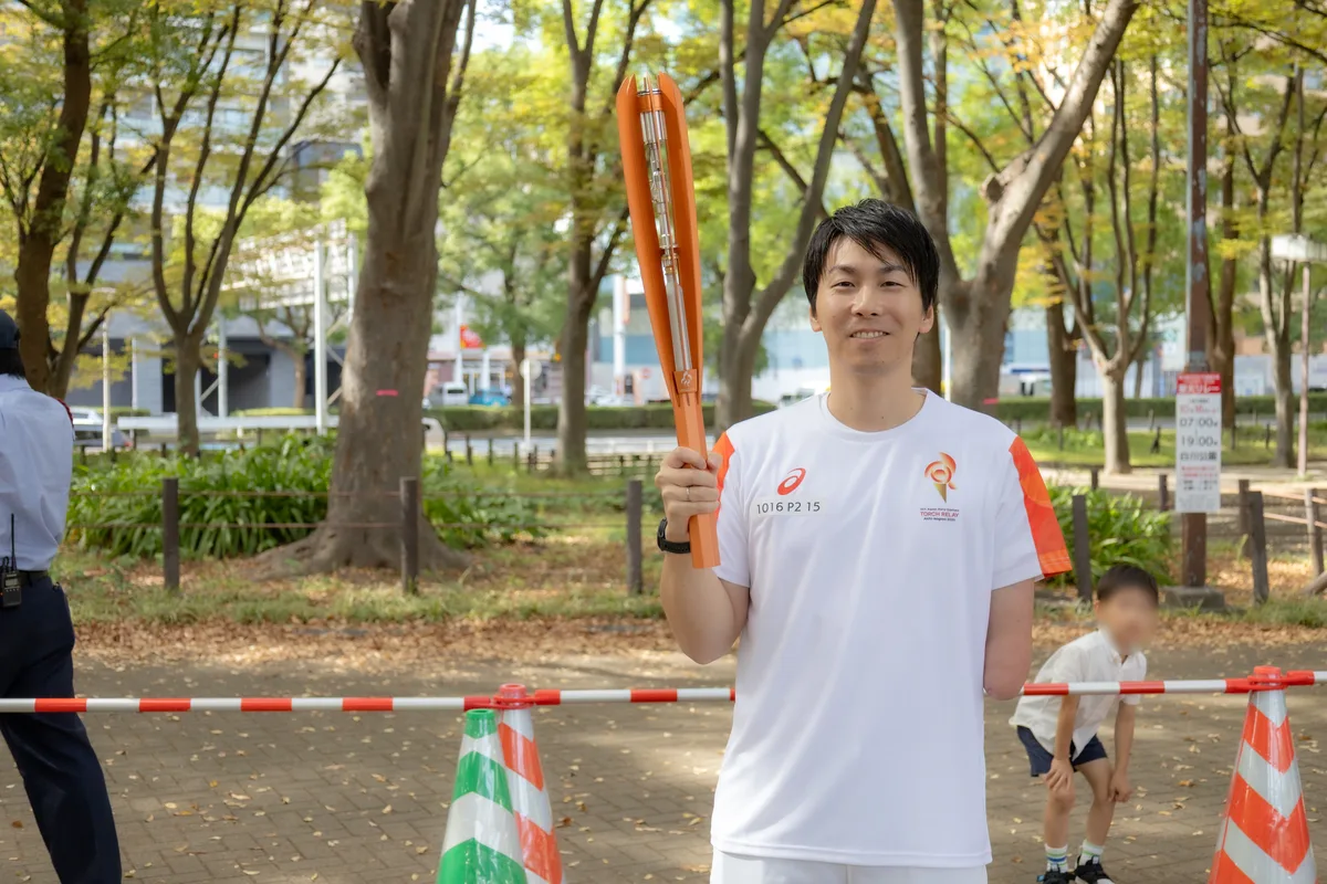 聖火トーチを掲げるパラ水泳の山田拓朗さん（白川公園）