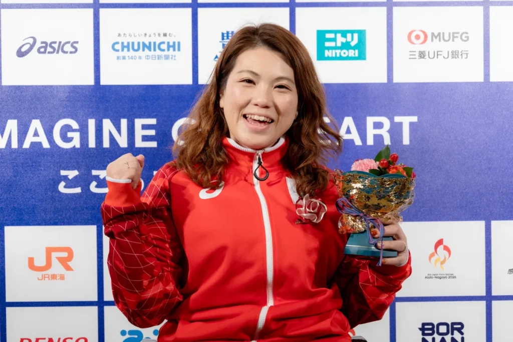 ミックスゾーンで花束を手にガッツポーズをするパラパワーリフティングの山本恵理選手